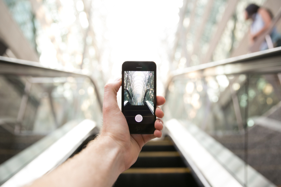 駅のエスカレーターでスマートフォンを手に持つ様子
