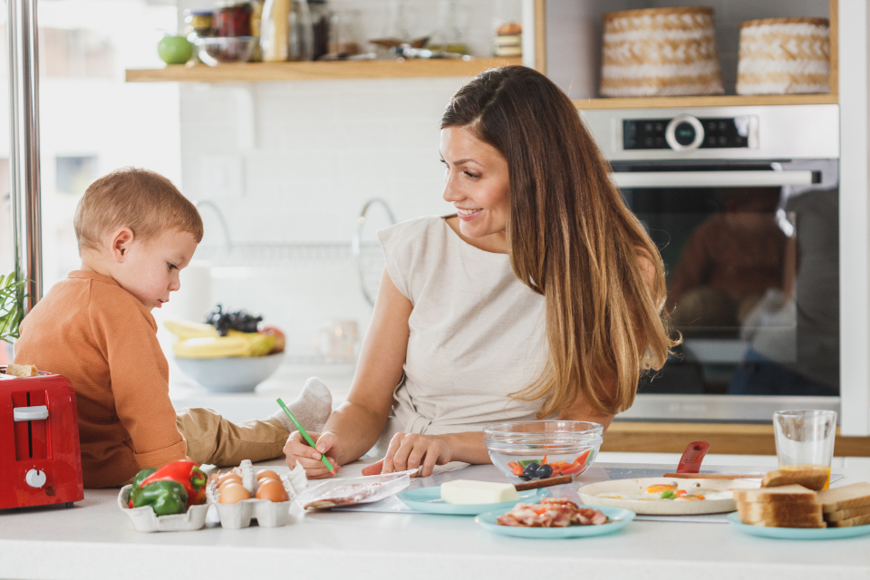 キッチンで子どもと一緒に料理をする母親